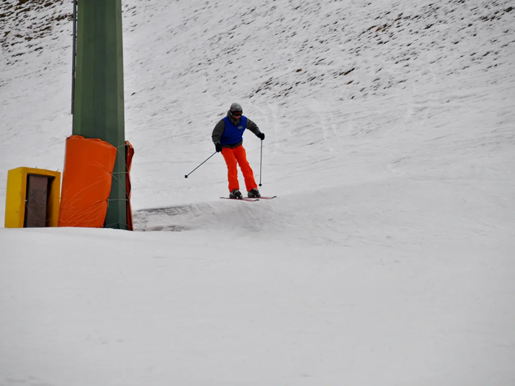 Skifahrer in roter Hose fährt an der Stütze vorbei.